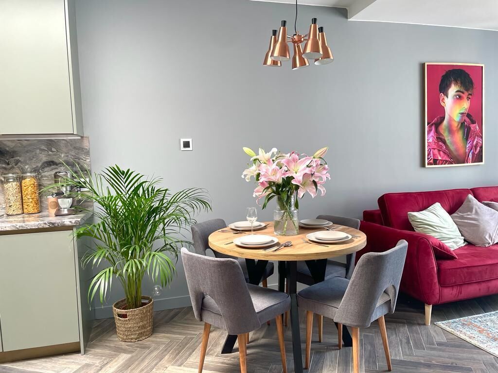 A modern dining area with a round table, grey chairs, and a vase of flowers.