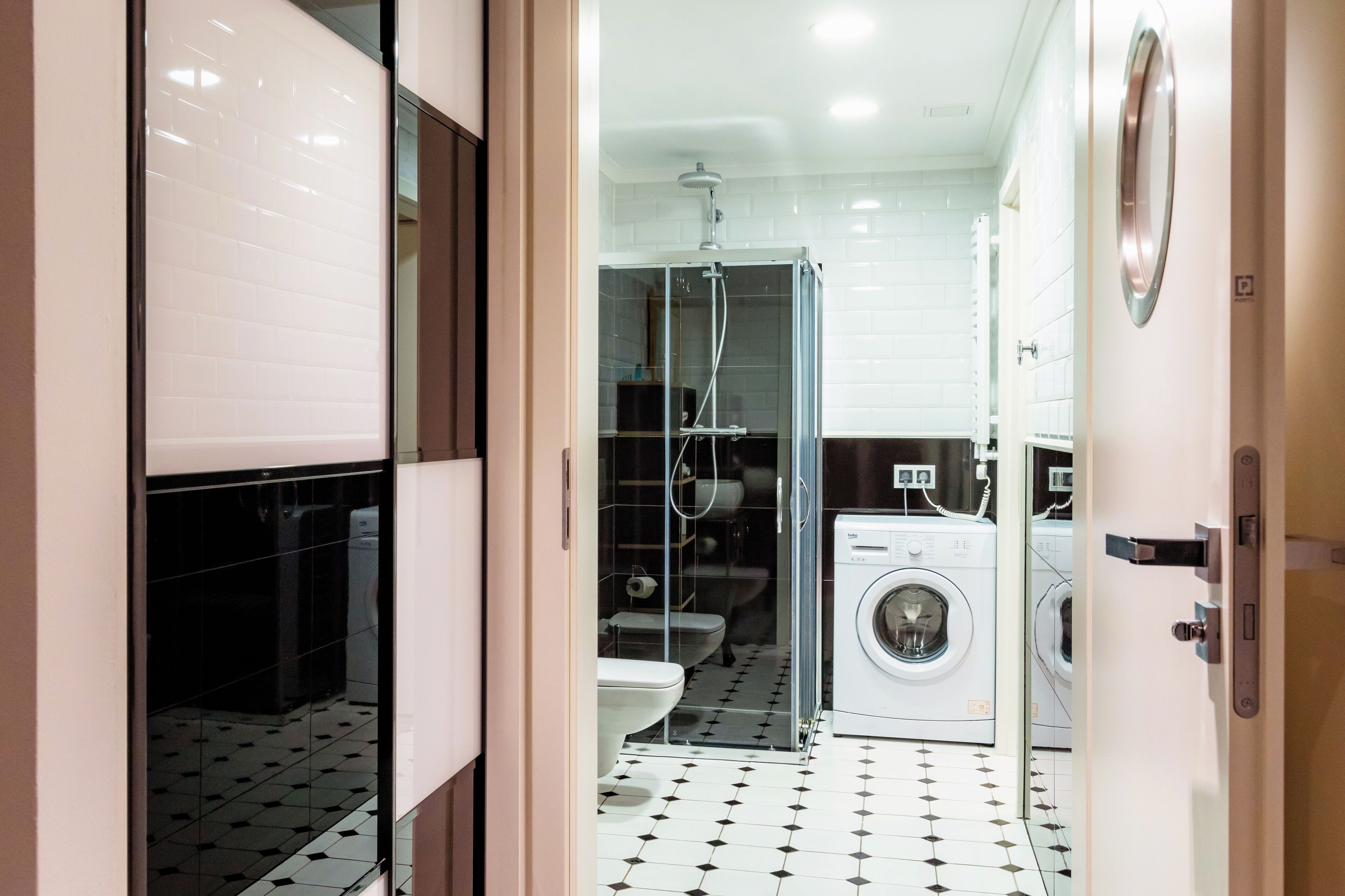 A modern bathroom with a glass shower enclosure, a toilet, a washing machine, and a sink.