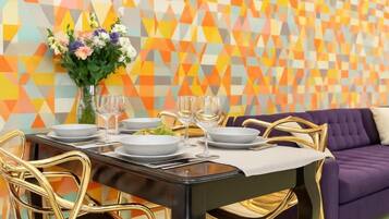 A dining area with a black table set for four, gold chairs, and a purple sofa in the background.