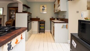 A compact kitchen with white cabinets, a wooden countertop, a stove, and a refrigerator. - Charming 3 Bedroom House next to Victoria Park | Pass the Keys (Bath)