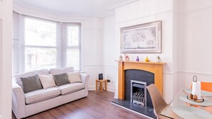 A modern living room with a fireplace, a sofa, and a dining table. - Pass the Keys | Comfortable Flat with Patio | Sleeps 4 (Westcliff-on-Sea)
