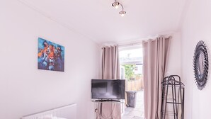 A bedroom with a bed, a television, a radiator, a painting, and a view of the outside. - Pass the Keys | Comfortable Flat with Patio | Sleeps 4 (Westcliff-on-Sea)
