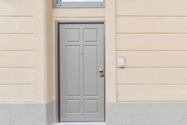 A closed door with a rectangular panel design, a round doorknob, and a small mailbox on the wall to the right.