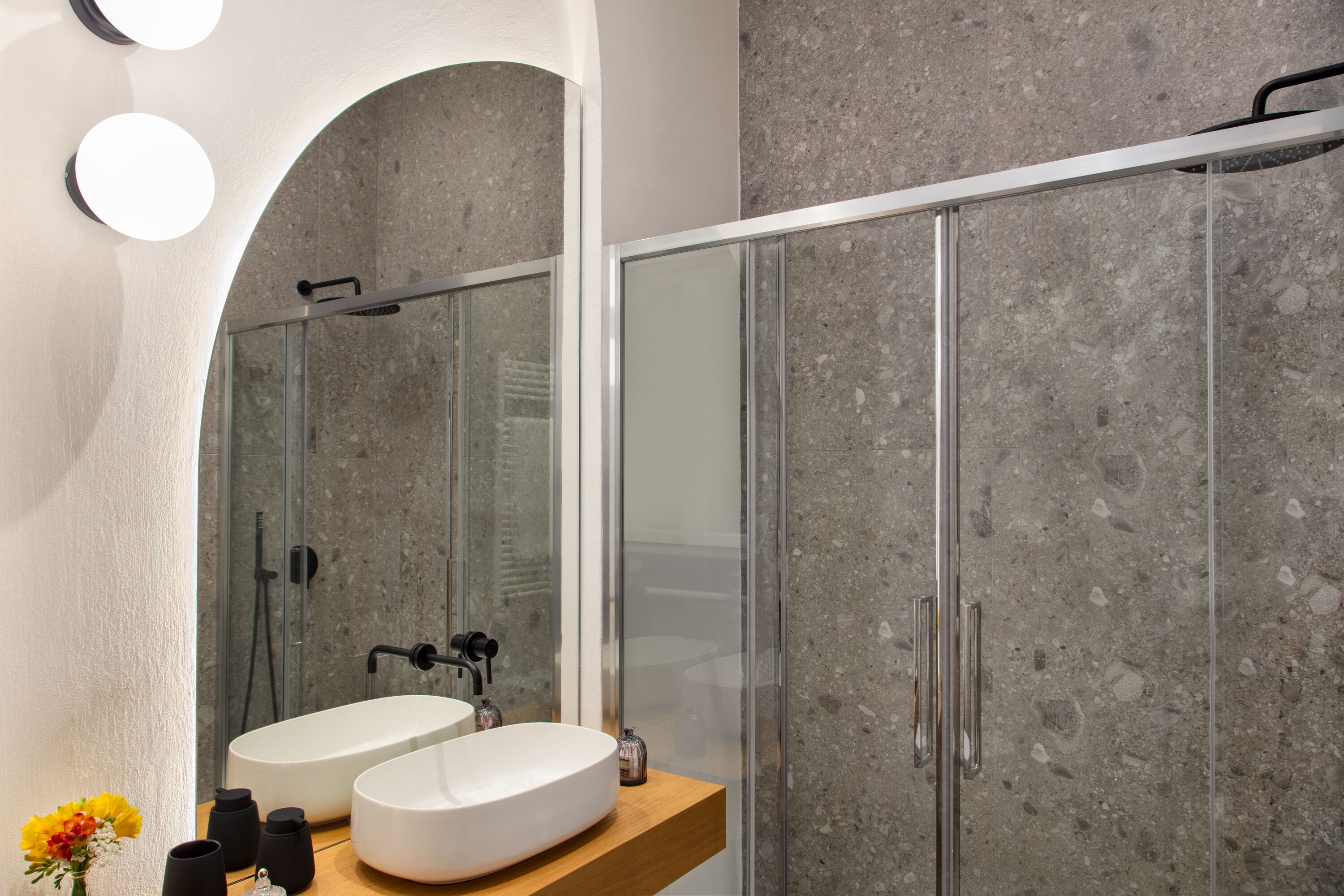 Un bagno moderno con un ampio specchio, due lavandini e una zona doccia.