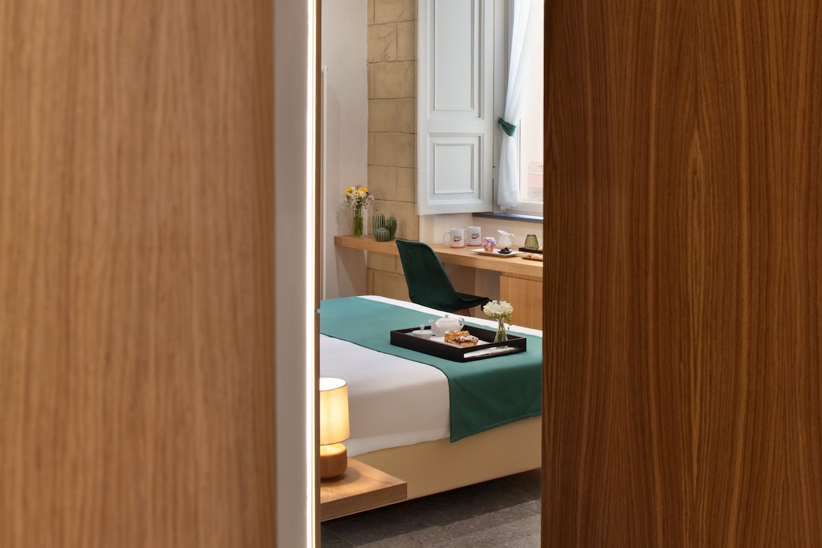 A modern bedroom with a bed, bedside table, lamp, and a window with curtains.
