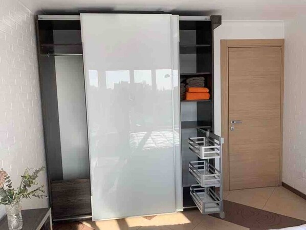 Une pièce dotée d’un placard avec une porte coulissante, d’une porte en bois et d’un sol carrelé.