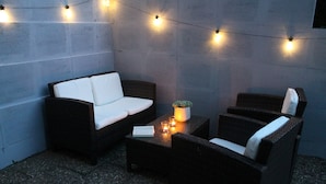 A cozy outdoor seating area with wicker furniture, string lights, and a small table with candles. - Apartment 'Apfelwiese' with Private Terrace, Garden, and Wi-Fi (Meßstetten)