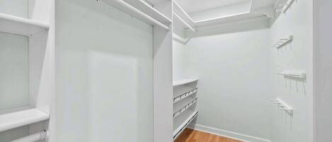 Un intérieur moderne et épuré, aux murs blancs, avec un plancher en bois, des étagères intégrées et un éclairage encastré au plafond.