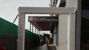 Een hotelingang met een bord waarop staat 'Hill View Lodging and Boarding'.