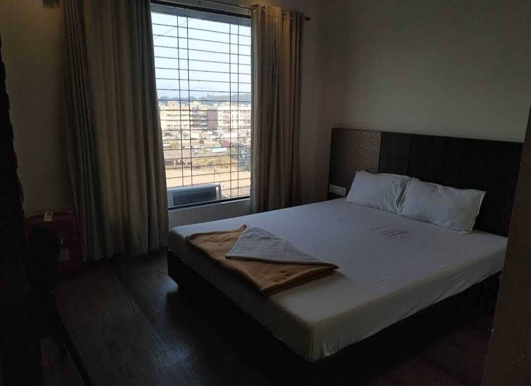 Une chambre d’hôtel avec un lit, une fenêtre avec des rideaux et une vue sur les bâtiments environnants.