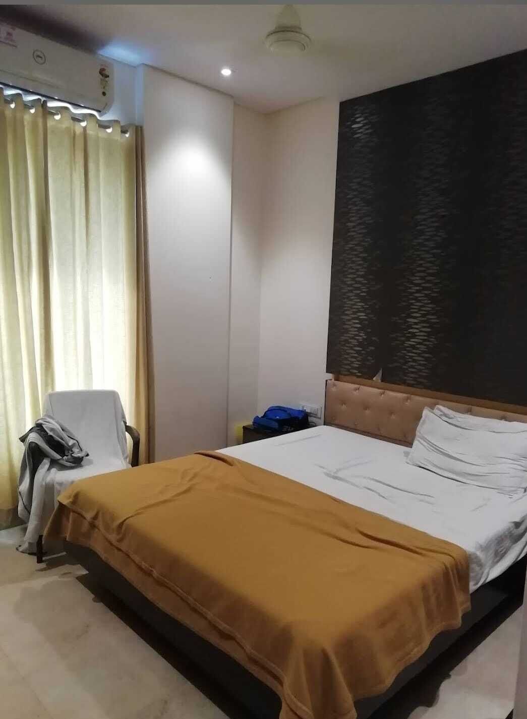 Ein Hotelzimmer mit einem Bett, einem Sessel, einem Schreibtisch und einer Wandklimaanlage.