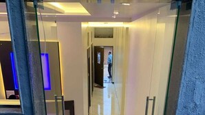 Een modern interieur met een glazen toegangsdeur naar een hal met een marmeren vloer, terwijl iemand er wegloopt.