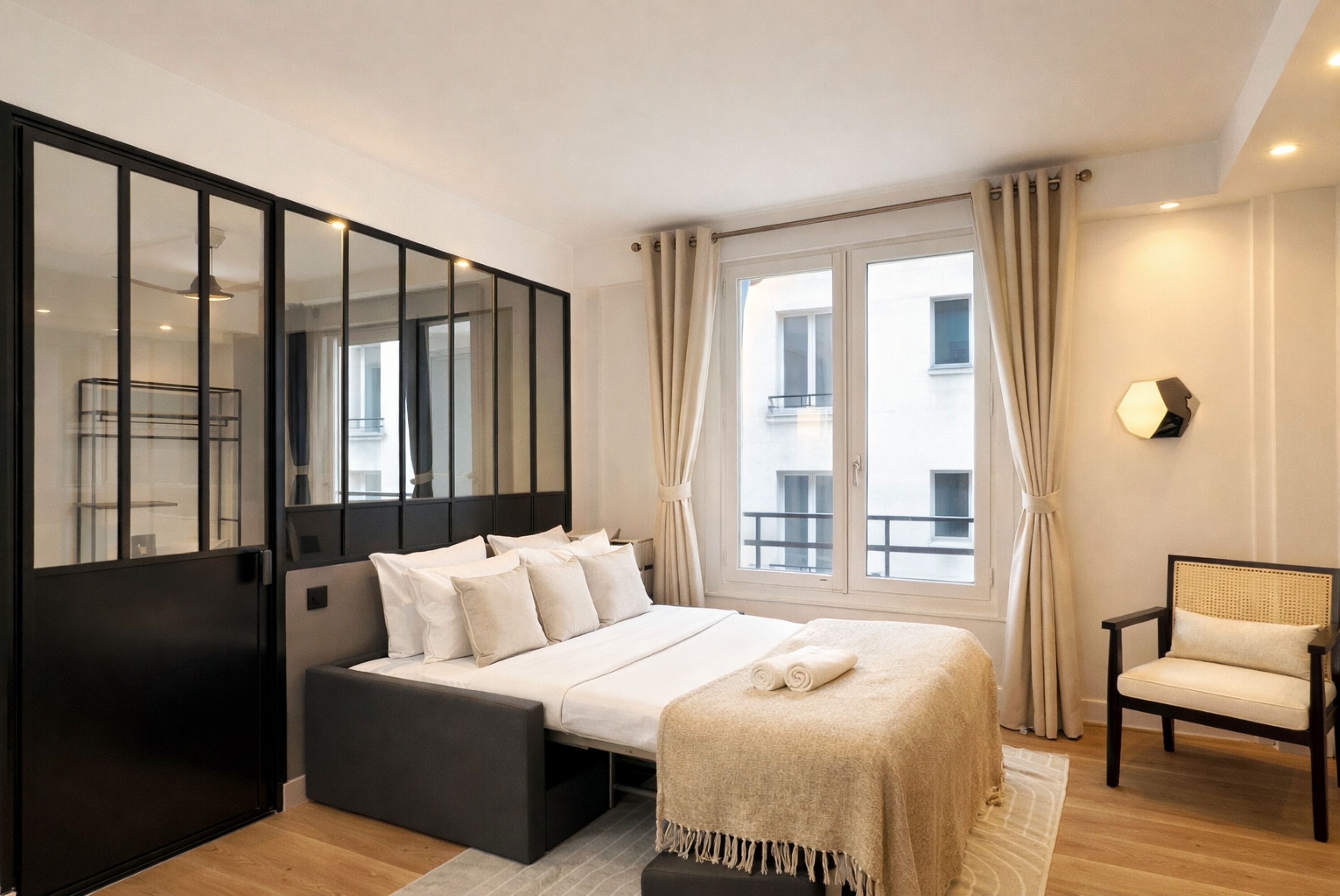 Ein modernes Schlafzimmer mit einem Bett, einem Sessel und einem großen Fenster.
