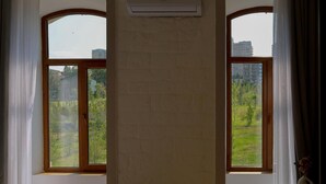 Una habitación con dos ventanas amplias, un muro de ladrillo y un equipo de aire acondicionado.