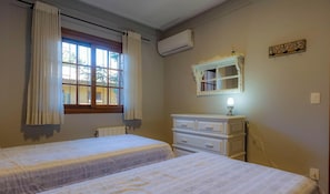 Une chambre avec deux lits, une commode, un miroir et un appareil de climatisation.