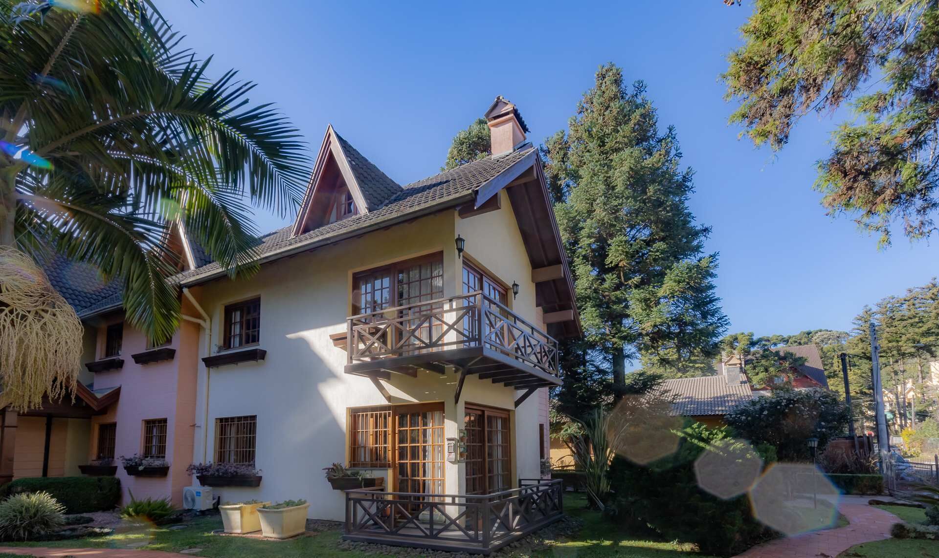 A two-story house with a balcony, large windows, and a garden.