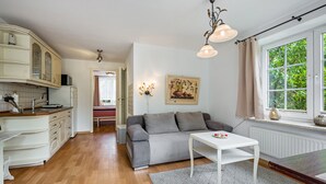 Eine moderne Küche mit weißen Schränken, einem grauen Sofa und einem weißen Tisch.