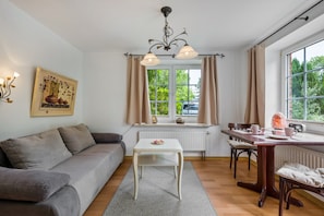 Una sala de estar moderna con sofá, mesa de comedor, candelabro y ventana con cortinas.