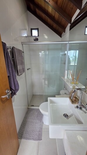 Ein modernes Badezimmer mit einer Duschkabine aus Glas, einem weißen Waschbecken und einer Toilette.