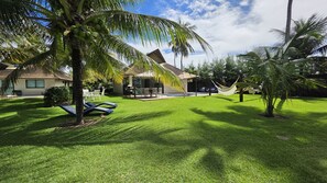 Ein gepflegter Rasen mit Pool, Palmen und Gartenmöbeln.