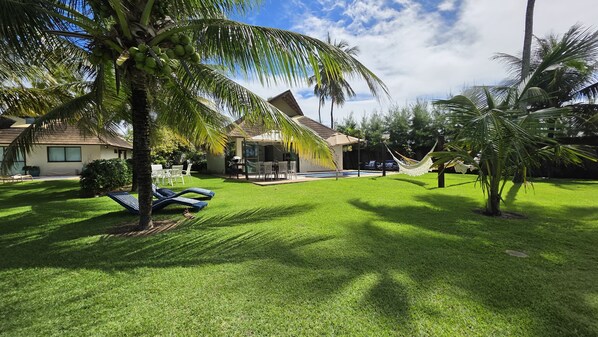 A well-maintained lawn with a pool, palm trees, and outdoor furniture.