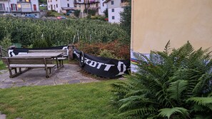 Un espace jardin agrémenté d’un banc en bois et d’une banderole noire avec du texte blanc.