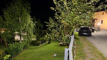 Vista nocturna d'una zona residencial amb una furgoneta aparcada, un jardí ben cuidat i una casa amb un porxo visible.