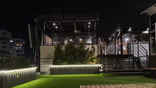 An outdoor area with artificial grass, a wooden bench, and a staircase leading to an upper level. - FF21-KDH (Bengaluru)