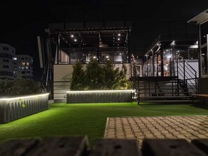 An outdoor area with artificial grass, a wooden bench, and a staircase leading to an upper level. - FF21-KDH (Bengaluru)