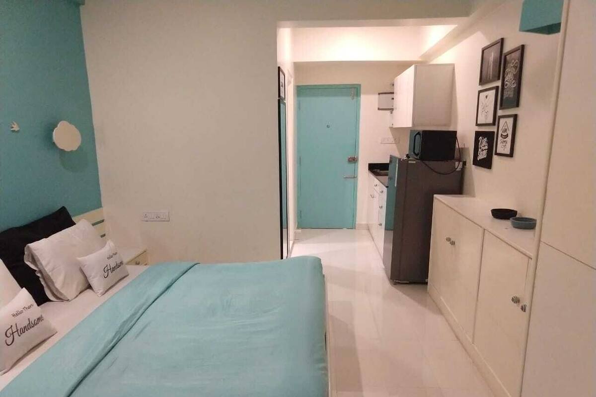 Un dormitorio con cama, escritorio y kitchenette.