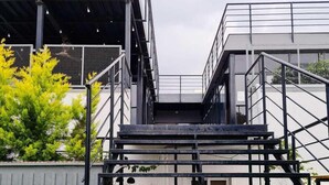 A set of outdoor stairs leading to a modern building with a metal railing and a grassy area in the foreground. - FF21-KDH (Bengaluru)