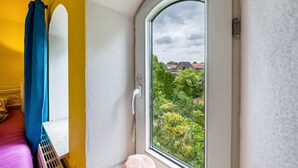 A room with a window, a radiator, and a bed with a blue curtain. - Room 'Single Room 2' with Wi-Fi (Neuenkirchen)