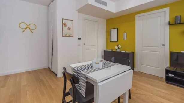 A compact living space with a dining area, a small kitchenette, and a yellow accent wall. - House Brembo (Milano)