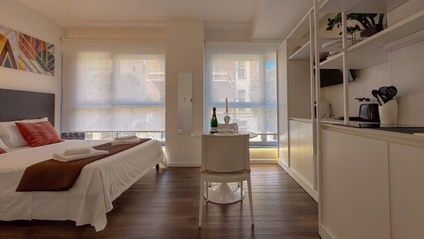 Ein Schlafzimmer mit einem Bett, einem kleinen Tisch mit einer Flasche und einem Sessel.