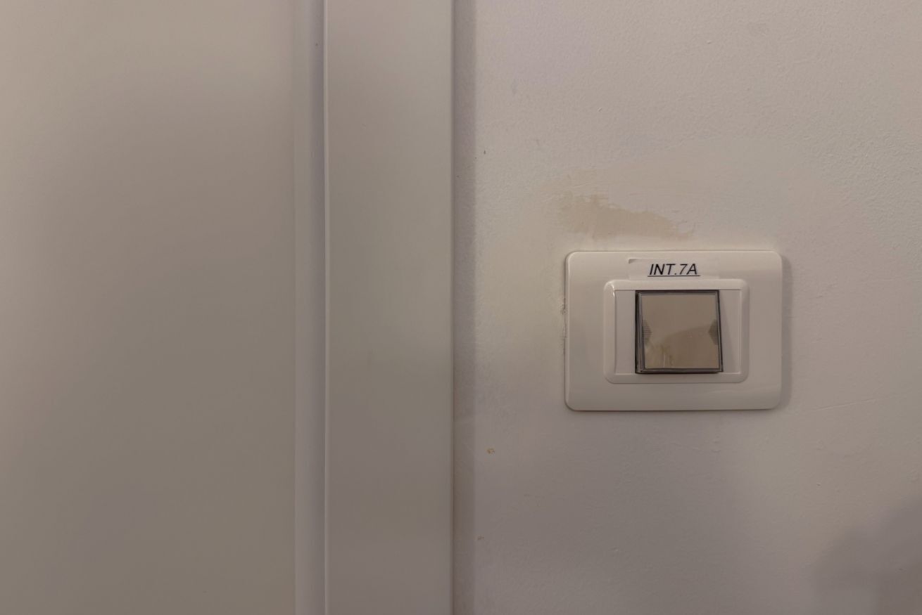 Eine weiße Wand mit einem weißen Schalter, auf dem 'INT.7A' steht.