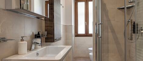 A modern bathroom with a large sink, a shower, and a toilet.