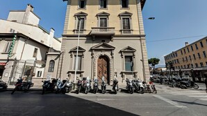 Un edificio histórico con una entrada central, numerosas ventanas y un balcón.