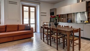 Una cocina moderna con armarios de madera, una mesa de comedor con sillas y un sofá en una sala de estar.