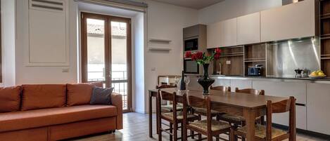 Una cocina moderna con armarios de madera, una mesa de comedor con sillas y un sofá en una sala de estar.