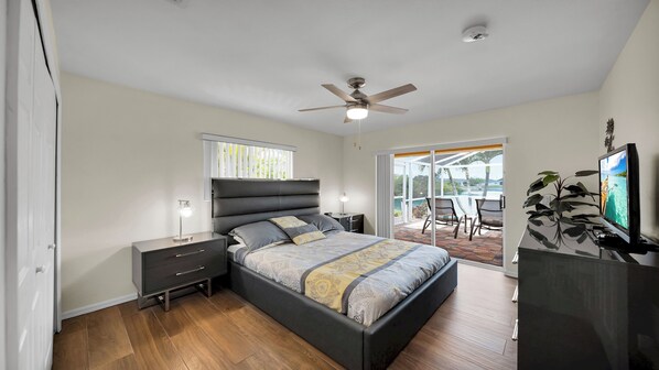 A modern bedroom with a bed, bedside tables, a ceiling fan, and a view of the outdoors.