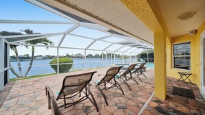 Un patio techado con mobiliario exterior y vista a un lago.