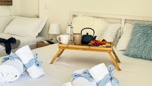 A neatly made bed with a tray of breakfast items, towels, and a bedside table with a lamp and a bottle. - Rooftop Blu Infinito by Ca-Sa Check (Chioggia)