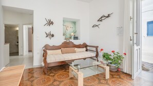A living room with a sofa, a glass coffee table, a potted plant, and wall art.