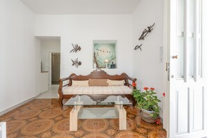 A room with a sofa, a glass coffee table, a painting, a potted plant, and a patterned floor. - Apartment 'Kallithea Beach' with Sea View, Wi-Fi and Air Conditioning (Myrtos)