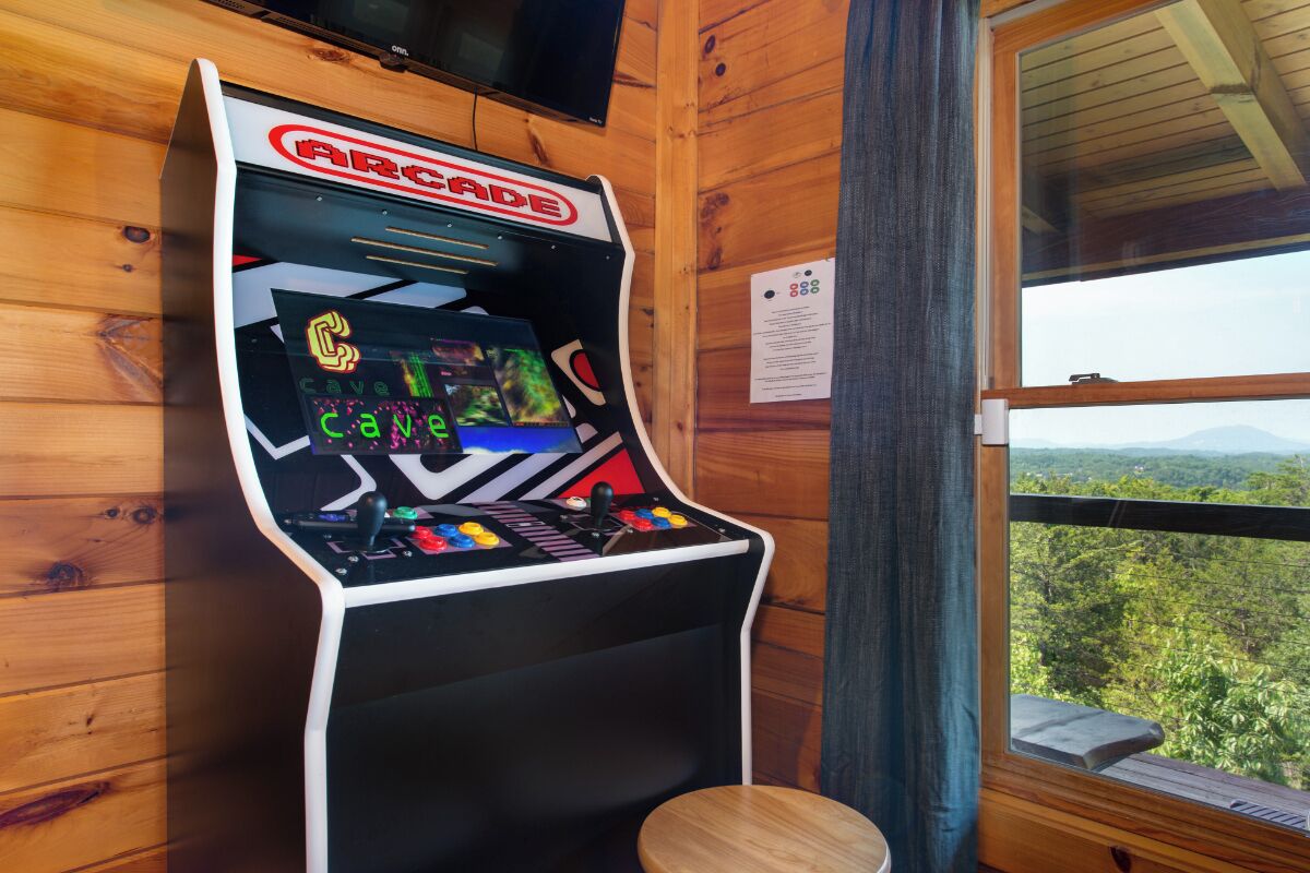Una máquina de juegos arcade con el rótulo "Arcade" y vistas a un bosque a través de una ventana.