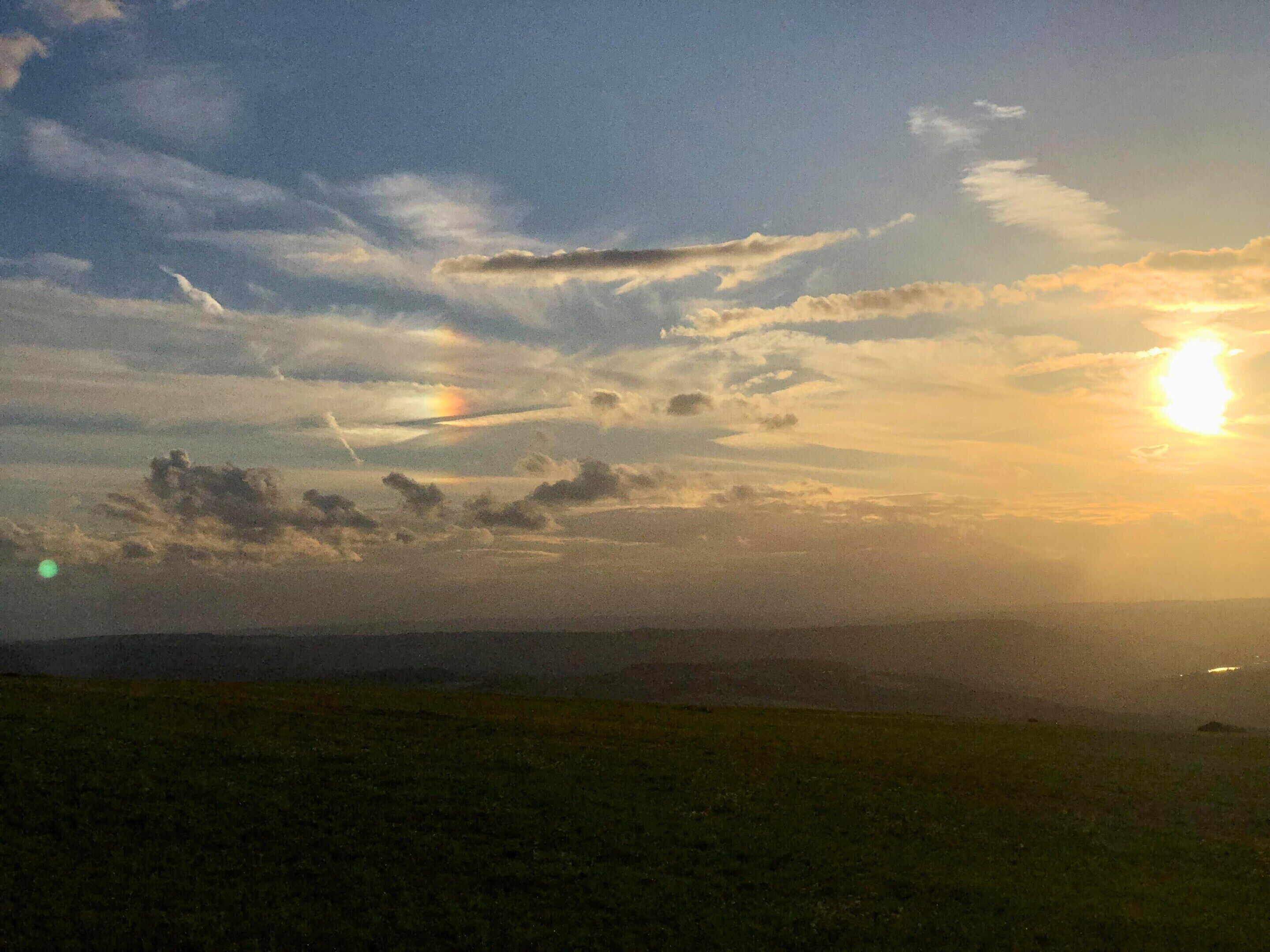 Un paisaje con atardecer, nubes y un horizonte lejano.