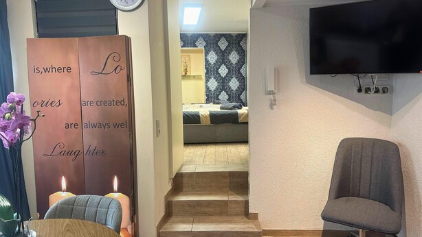 Ein Zimmer mit einem Bett, einem Sessel und einem an der Wand befestigten Fernseher.