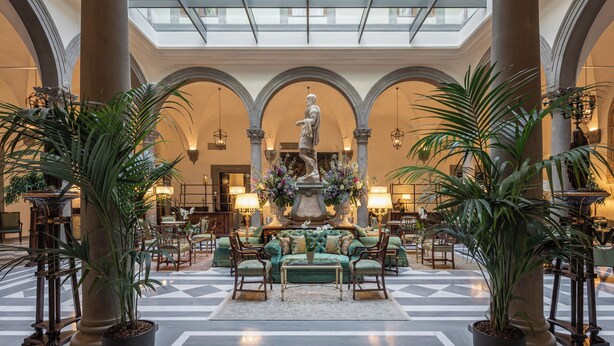A spacious lobby with a high ceiling, large columns, and a central fountain.