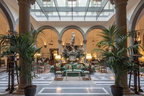 Un'ampia hall con soffitto alto, grandi colonne e una fontana al centro.