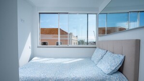 A bedroom with a large window, a bed with patterned bedding, and a view of buildings outside. - 7 Night Discount- Lagos Marina- Doublebed (Lagos)